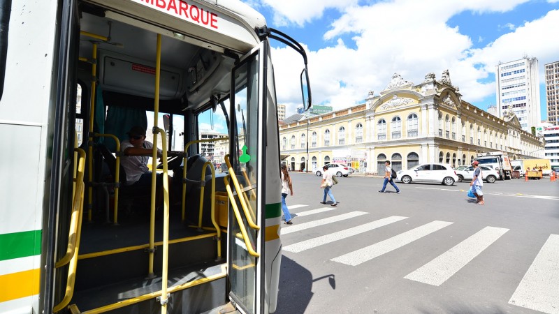 Foto horizontal mostra foto das portas abertas de um &ocirc;nibus de Porto Alegre &agrave; direita. Ao fundo se v&ecirc; o Mercado P&uacute;blico de Porto Alegre.